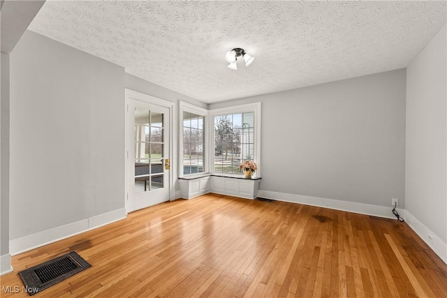 spare room featuring a textured ceiling and light hardwood / wood-style flooring