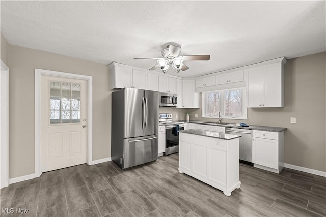 kitchen with a center island, sink, dark wood-type flooring, stainless steel appliances, and white cabinets