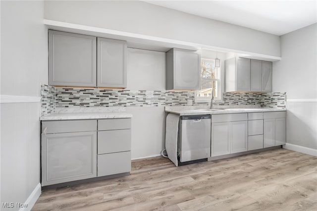 kitchen with sink, light hardwood / wood-style flooring, stainless steel dishwasher, decorative backsplash, and gray cabinets