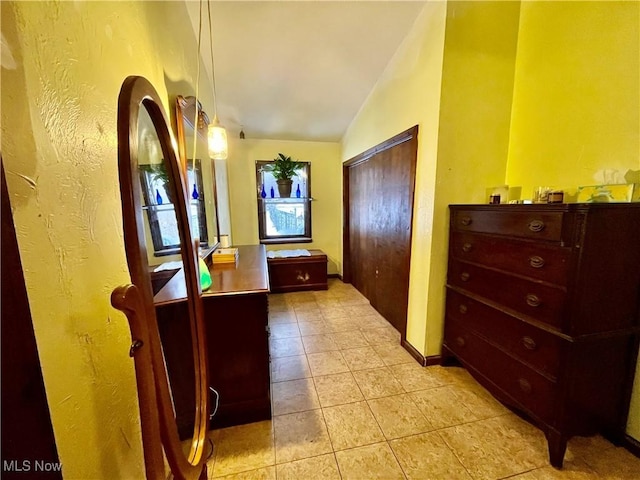 hallway with light tile patterned floors and vaulted ceiling