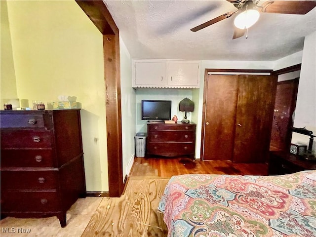 bedroom featuring ceiling fan, a closet, a textured ceiling, and light hardwood / wood-style flooring