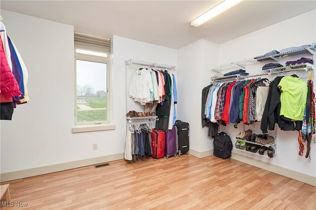 walk in closet with light hardwood / wood-style floors