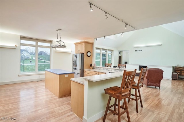 kitchen featuring kitchen peninsula, a wealth of natural light, hanging light fixtures, and stainless steel refrigerator with ice dispenser