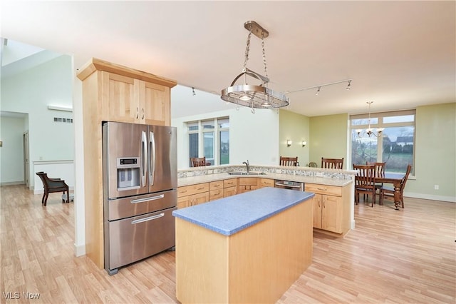 kitchen with kitchen peninsula, appliances with stainless steel finishes, light wood-type flooring, light brown cabinets, and decorative light fixtures