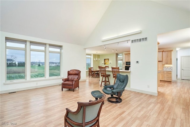 interior space featuring a notable chandelier, light hardwood / wood-style floors, and high vaulted ceiling