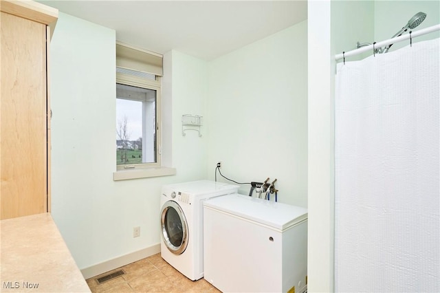 laundry area with separate washer and dryer and light tile patterned floors