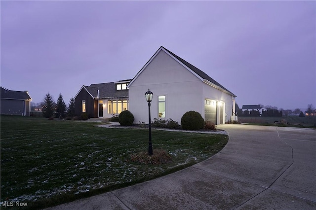 property exterior at dusk with a lawn and a garage