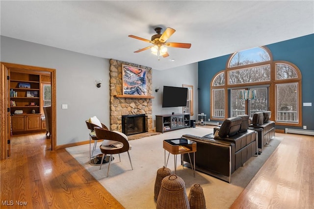 living room featuring ceiling fan, light hardwood / wood-style floors, a fireplace, and a baseboard radiator