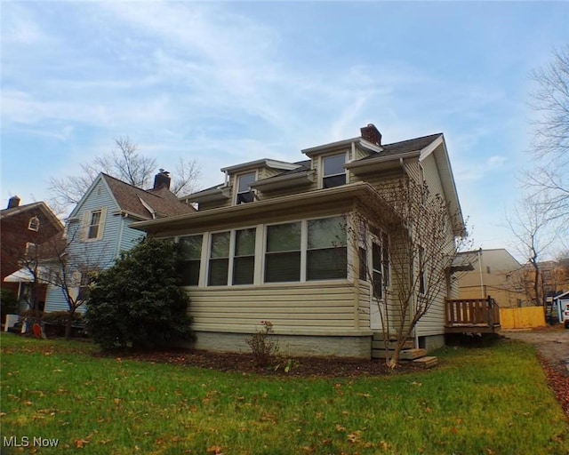 view of side of home with a lawn and a sunroom