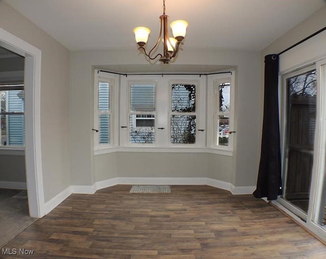 unfurnished dining area with a chandelier and dark hardwood / wood-style floors