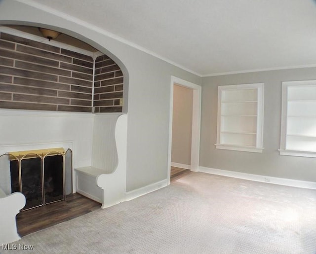 interior space featuring built in shelves, crown molding, and carpet floors