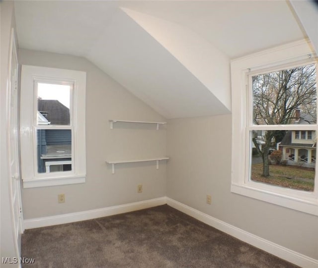 additional living space with dark carpet, vaulted ceiling, and plenty of natural light