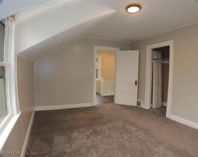 additional living space with dark carpet and lofted ceiling