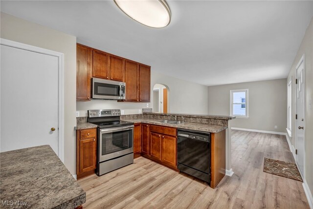 kitchen with kitchen peninsula, sink, light hardwood / wood-style floors, and appliances with stainless steel finishes