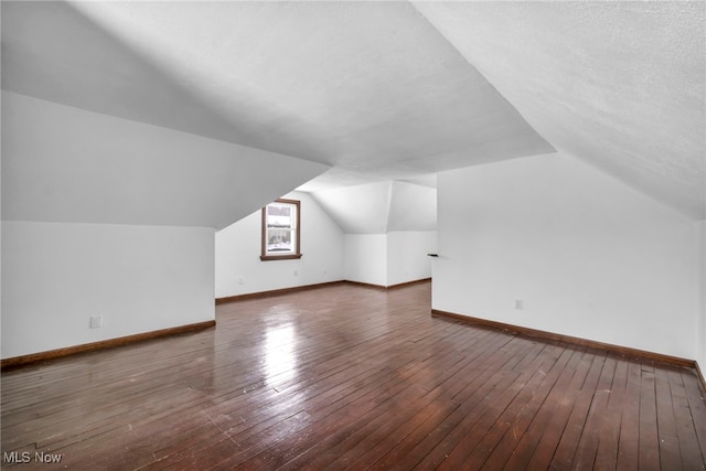 bonus room with a textured ceiling, dark hardwood / wood-style flooring, and lofted ceiling