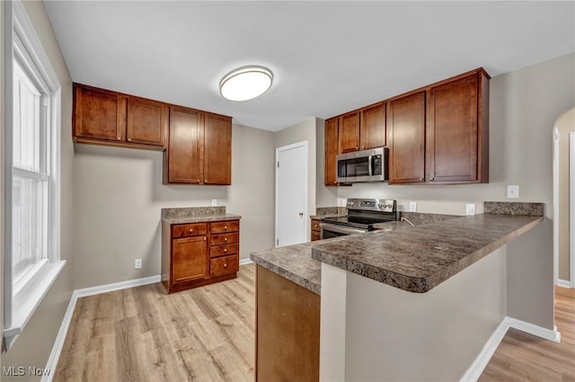 kitchen with kitchen peninsula, appliances with stainless steel finishes, light wood-type flooring, and a breakfast bar area