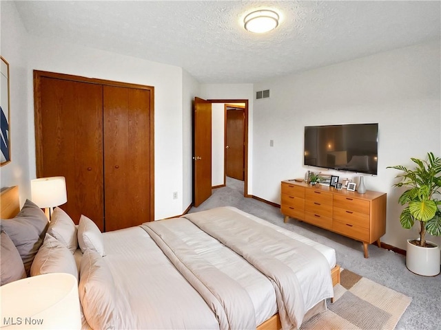 carpeted bedroom with a textured ceiling and a closet