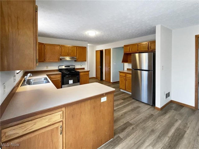 kitchen featuring sink, dark hardwood / wood-style floors, a textured ceiling, kitchen peninsula, and stainless steel appliances