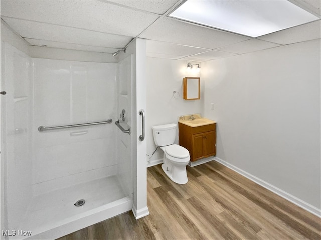 bathroom featuring a paneled ceiling, vanity, hardwood / wood-style floors, a shower, and toilet