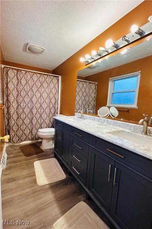 bathroom featuring toilet, vanity, a textured ceiling, and hardwood / wood-style flooring