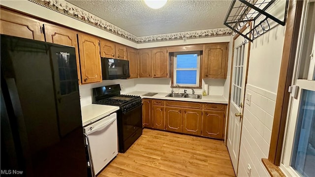 kitchen with sink, black appliances, a textured ceiling, and light hardwood / wood-style floors