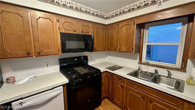 kitchen featuring black appliances, light hardwood / wood-style flooring, sink, and a textured ceiling