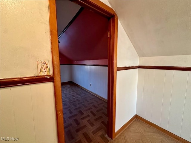 bonus room featuring parquet flooring, wooden walls, and vaulted ceiling