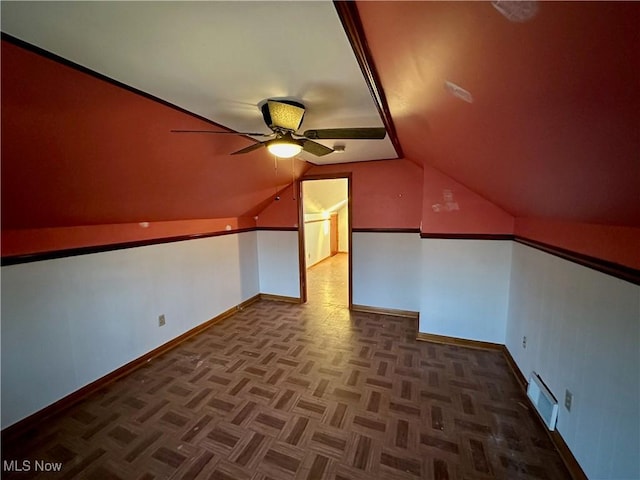 additional living space with dark parquet floors, ceiling fan, and vaulted ceiling