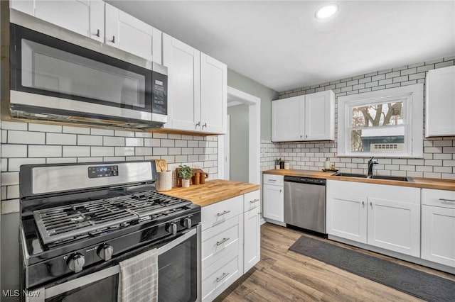 kitchen featuring white cabinets, sink, appliances with stainless steel finishes, and wooden counters