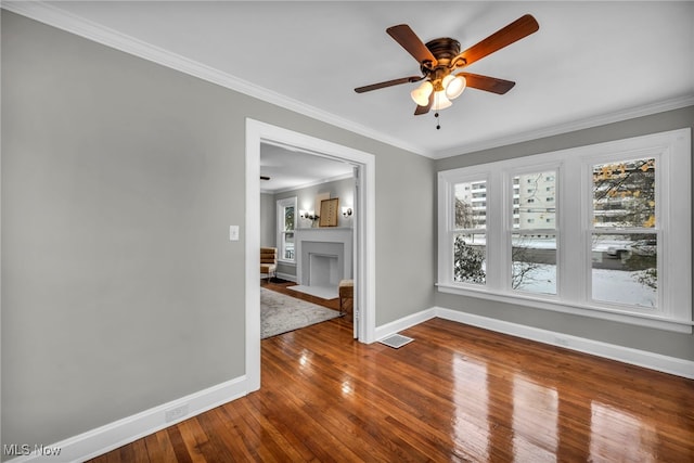 spare room featuring ceiling fan, wood-type flooring, and ornamental molding