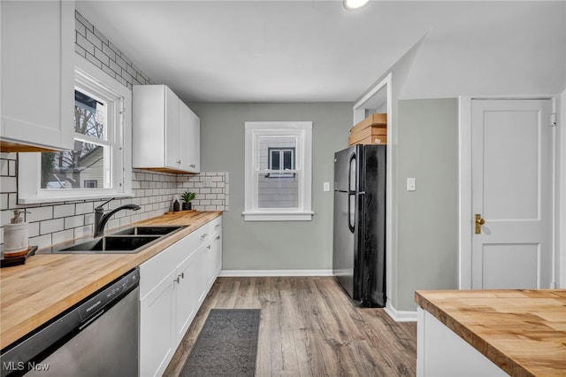 kitchen with black fridge, sink, stainless steel dishwasher, and wood counters