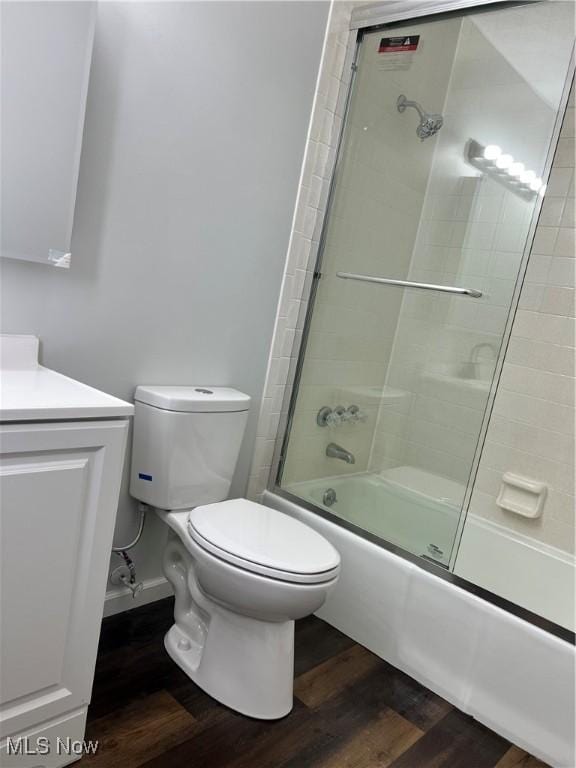 full bathroom featuring hardwood / wood-style floors, vanity, toilet, and shower / bath combination with glass door