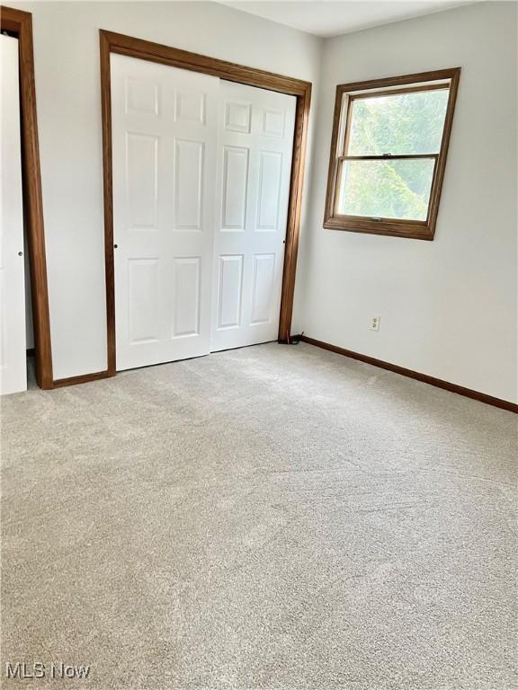 unfurnished bedroom featuring light colored carpet and a closet