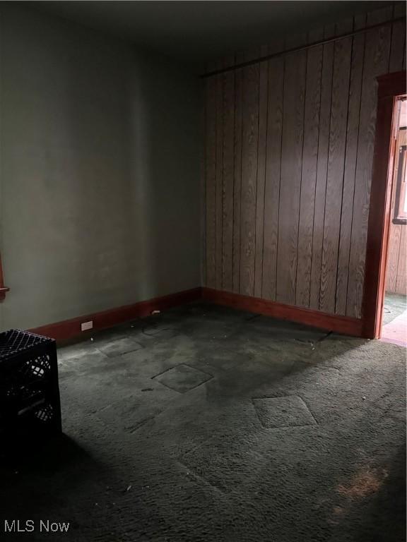 unfurnished room with carpet flooring and wooden walls