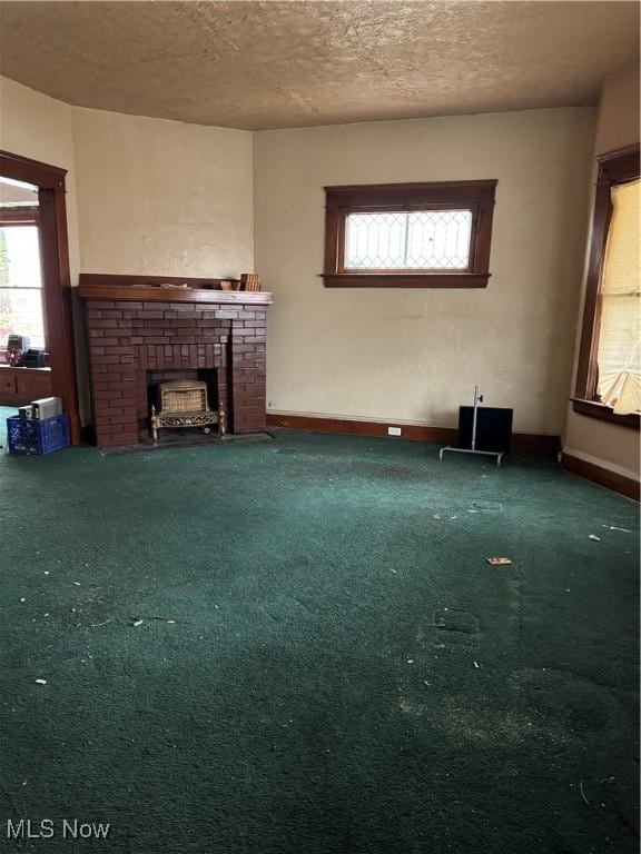 unfurnished living room featuring dark colored carpet, a textured ceiling, and a brick fireplace