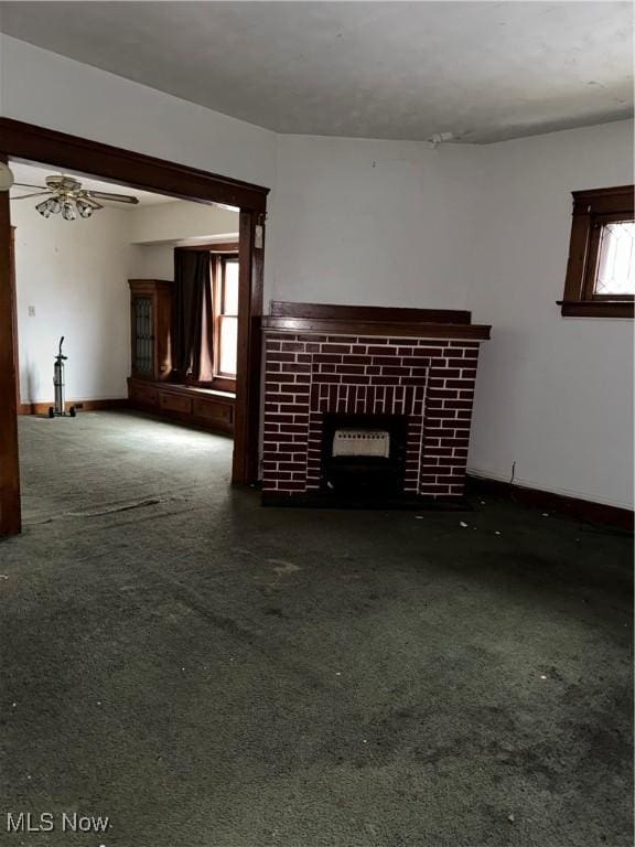 unfurnished living room featuring a fireplace, dark colored carpet, plenty of natural light, and ceiling fan