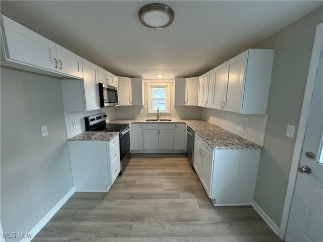 kitchen featuring white cabinets, sink, appliances with stainless steel finishes, and light hardwood / wood-style flooring