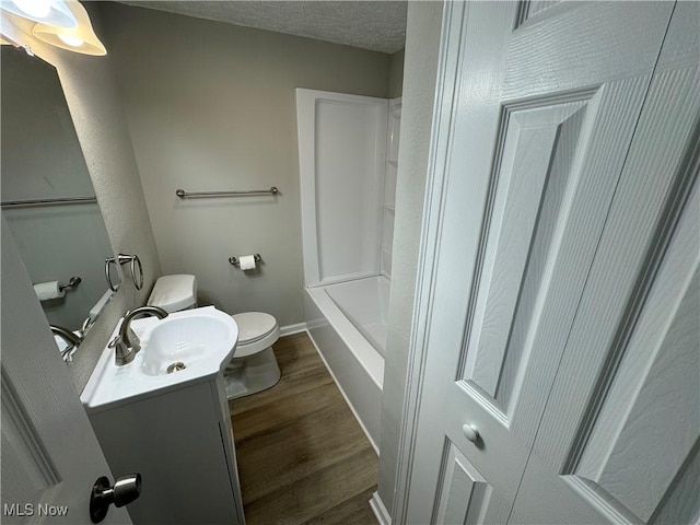 bathroom featuring hardwood / wood-style floors, vanity, toilet, and a textured ceiling