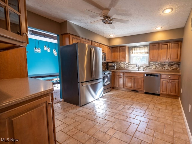 kitchen featuring ceiling fan, backsplash, decorative light fixtures, a textured ceiling, and appliances with stainless steel finishes