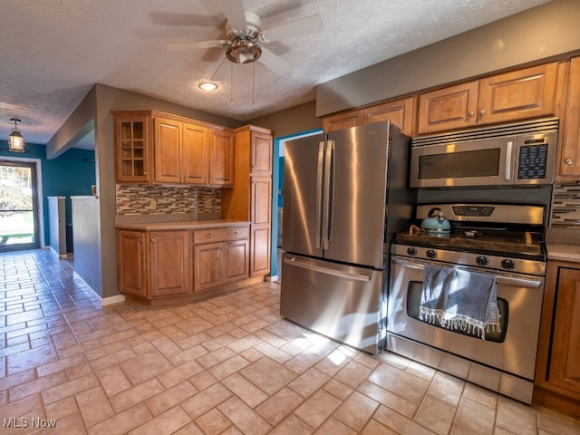 kitchen featuring a textured ceiling, backsplash, stainless steel appliances, and ceiling fan