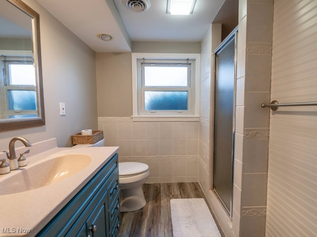 bathroom featuring an enclosed shower, wood-type flooring, vanity, and tile walls