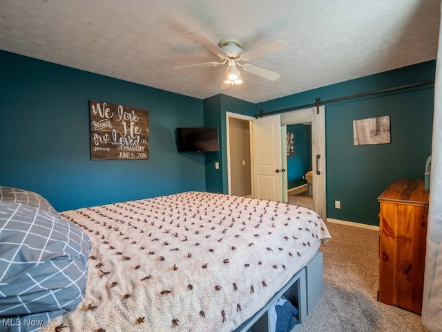 bedroom with carpet, ceiling fan, a barn door, and a textured ceiling