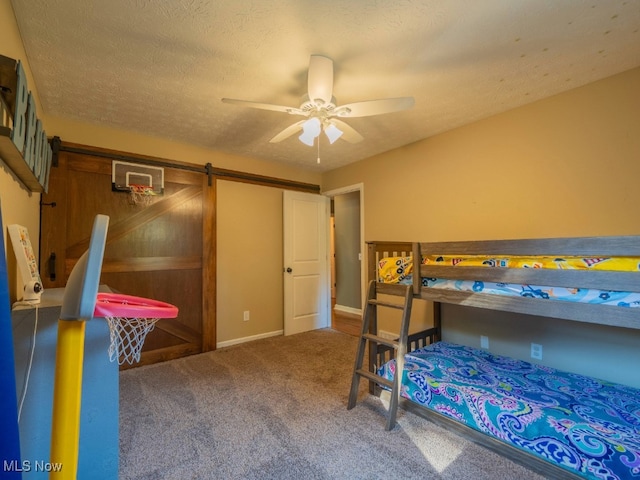 carpeted bedroom with ceiling fan, a barn door, and a textured ceiling