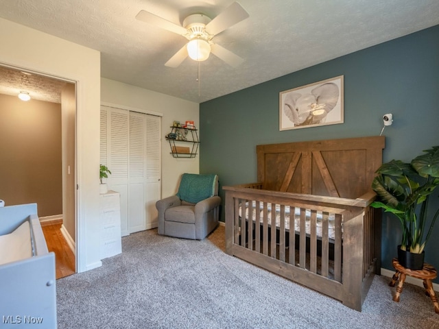 bedroom featuring a textured ceiling, ceiling fan, light carpet, and a closet