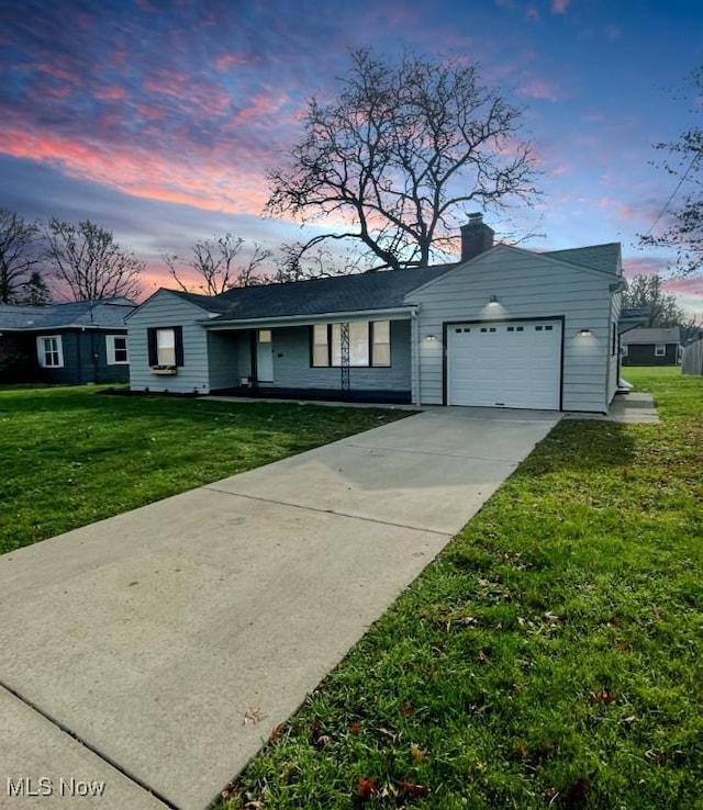 ranch-style home with a garage, a porch, and a lawn