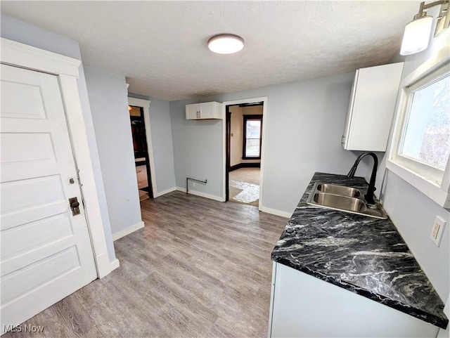 kitchen featuring light hardwood / wood-style flooring, white cabinetry, a healthy amount of sunlight, and sink