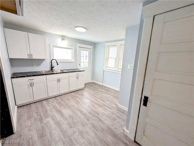 kitchen featuring white cabinetry, sink, a textured ceiling, and light hardwood / wood-style flooring