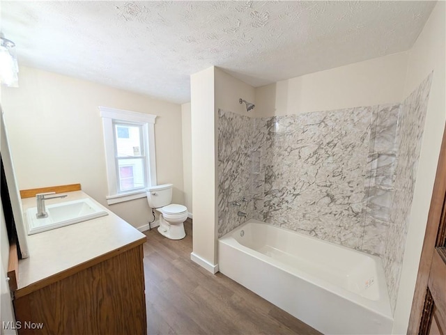 full bathroom with bathing tub / shower combination, hardwood / wood-style floors, a textured ceiling, toilet, and vanity