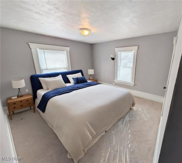 carpeted bedroom featuring multiple windows and a textured ceiling