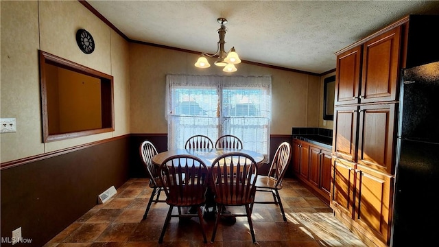 dining room with vaulted ceiling, ornamental molding, a textured ceiling, and an inviting chandelier